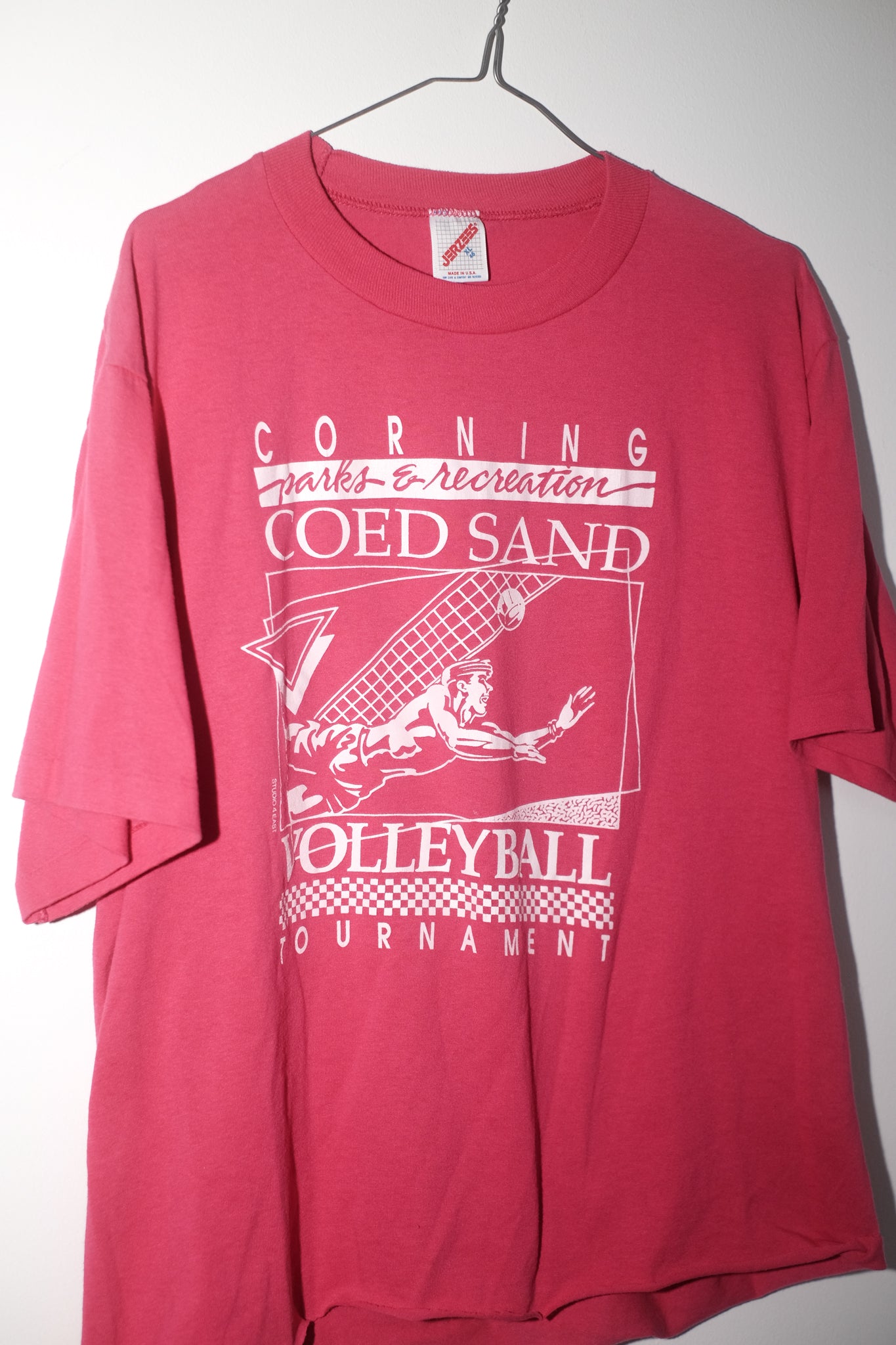 Red t-shirt with white graphic and text on a hanger against a white background